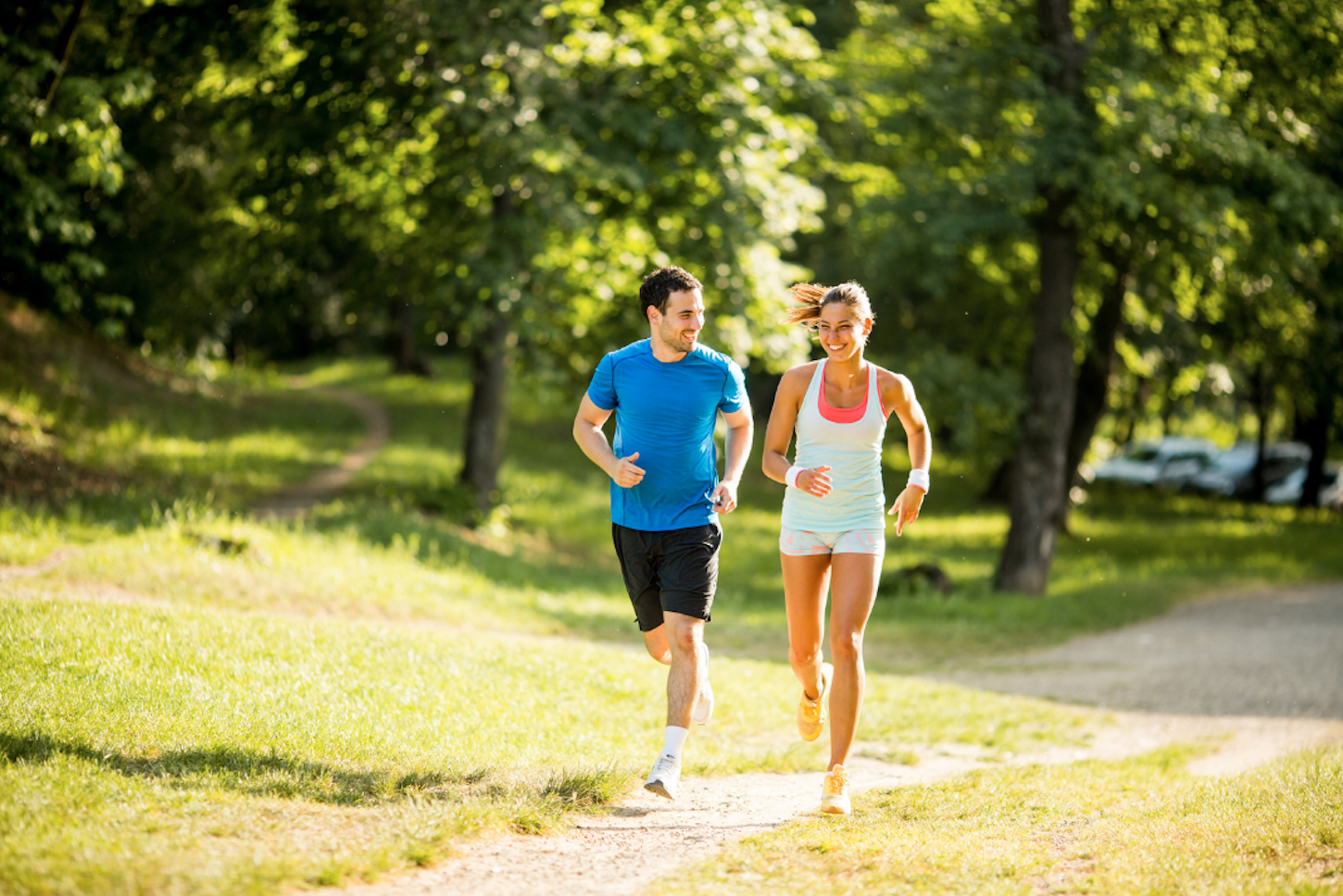 two people smiling running on a trail in a park
